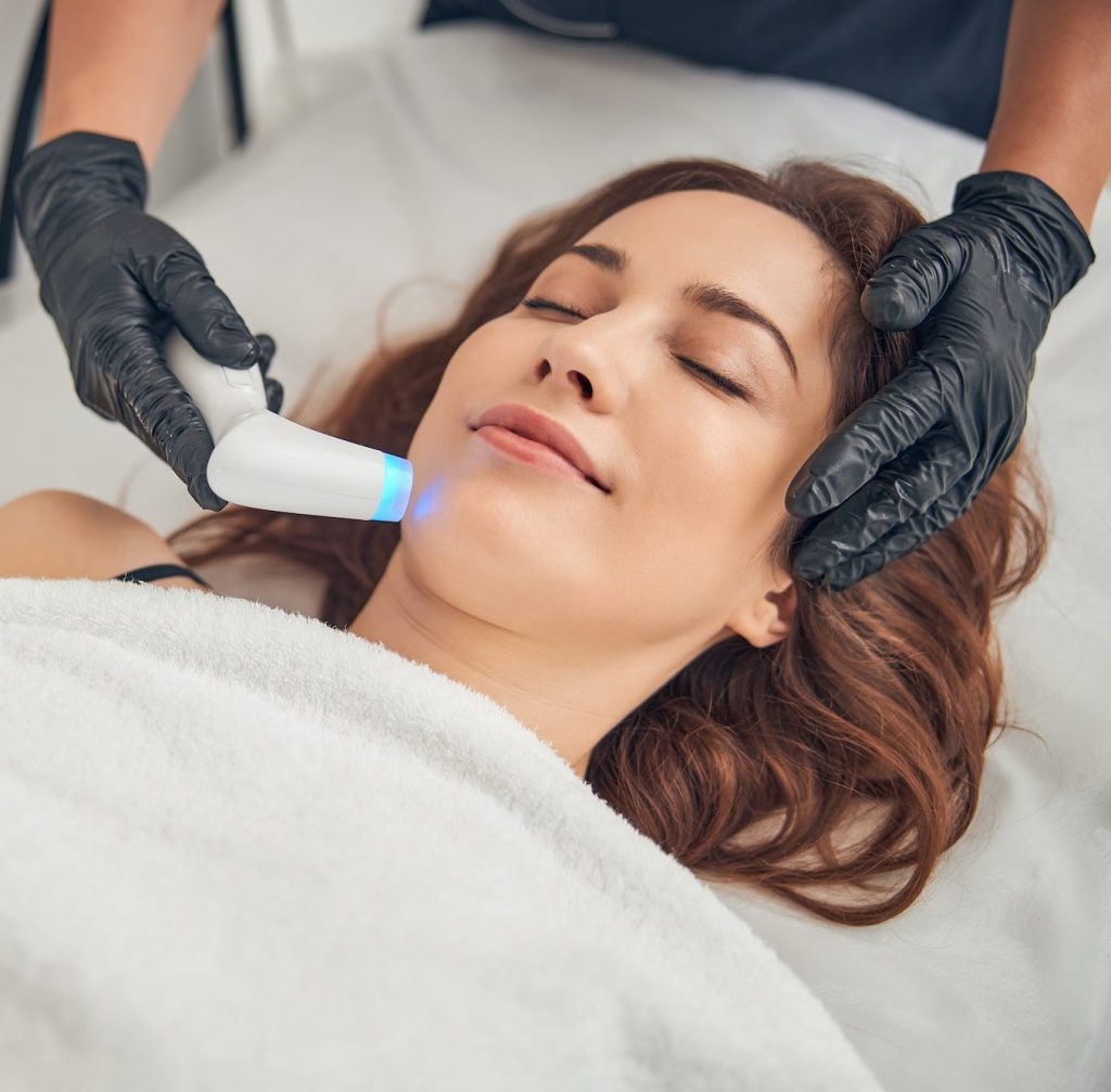 Beautician reducing wrinkles on chin of client