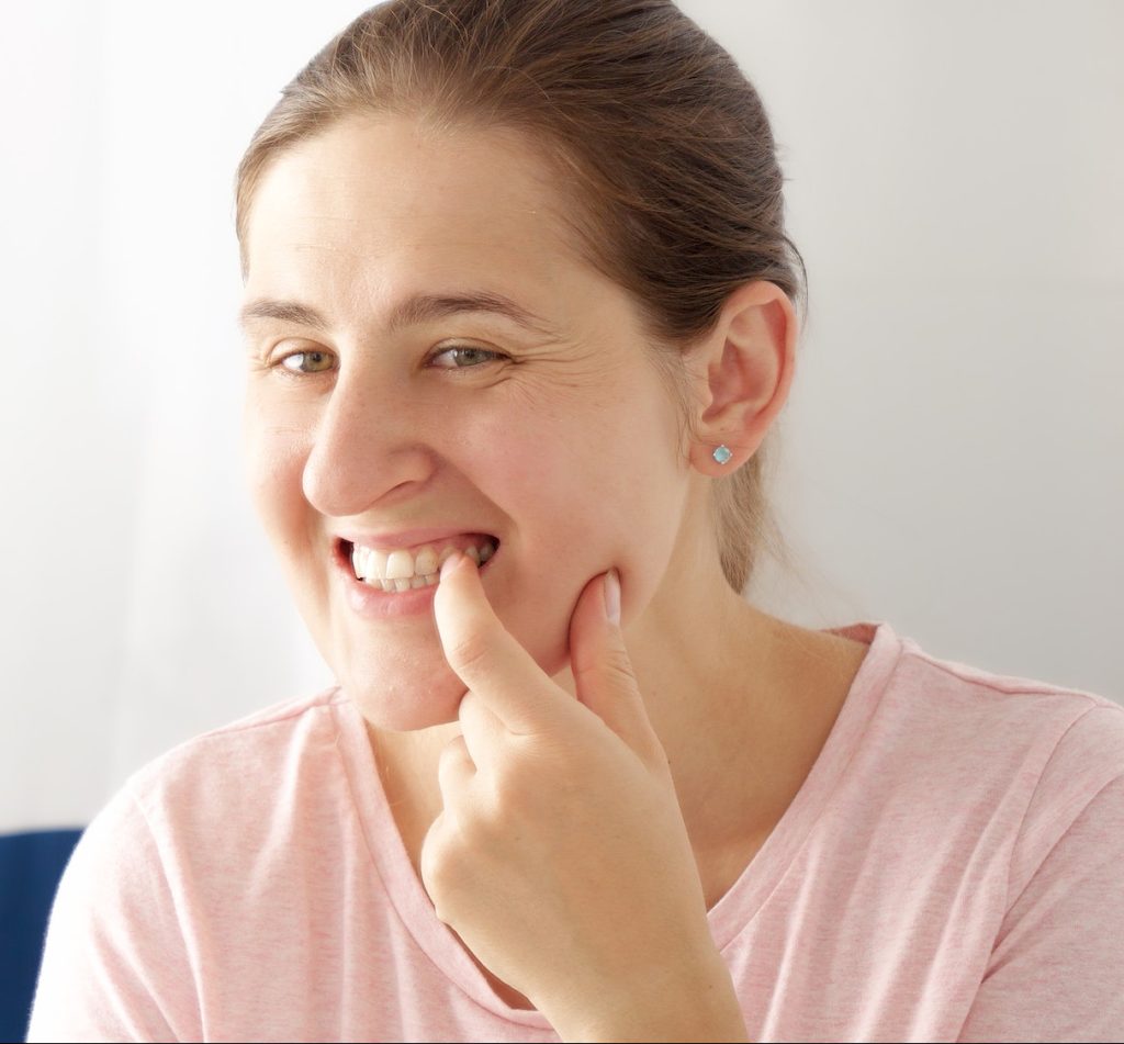 Portrait of beautiful smiling woman checking her teeth and rubbing them with finger