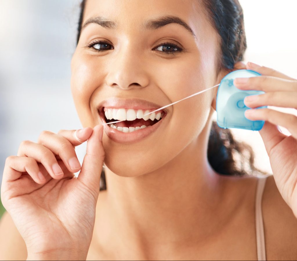 Dental hygiene is a priority. Shot of a young woman flossing her teeth at home. Greatest Smile Dentistry